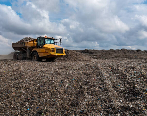 A dumper truck on a large waste management landfill site dumping rubbish in an environmental issue image